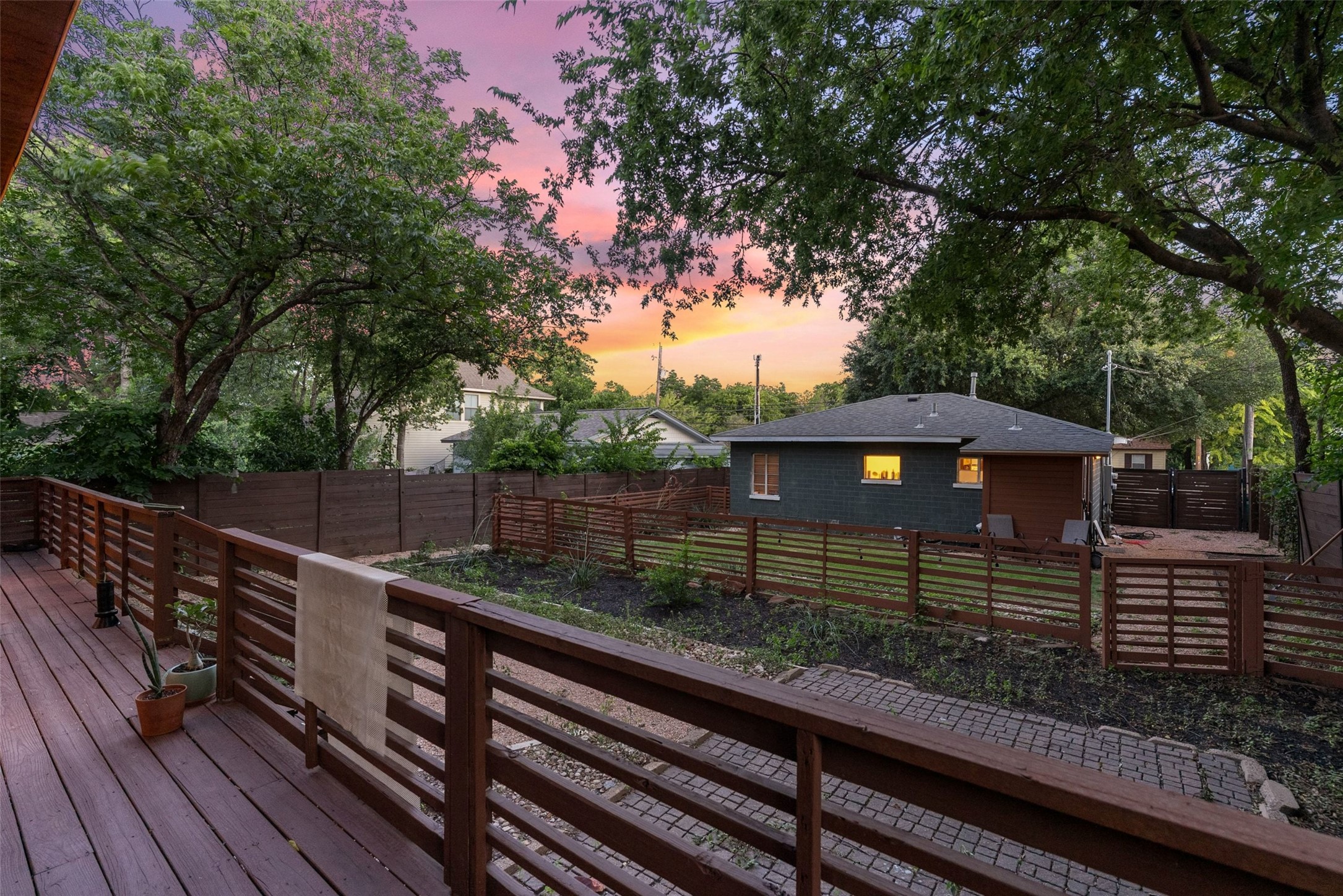 412 West Croslin Street Austin, TX 78752 - Photo 34 of 36 A spacious wooden deck overlooks a tranquil yard with a modern fence, offering serene outdoor living.