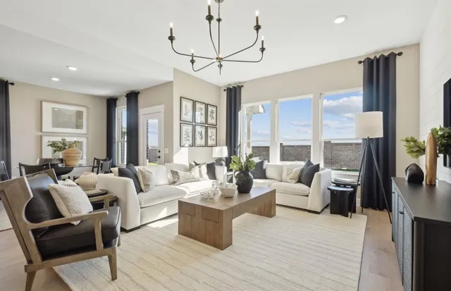 a living room with furniture large windows and a chandelier