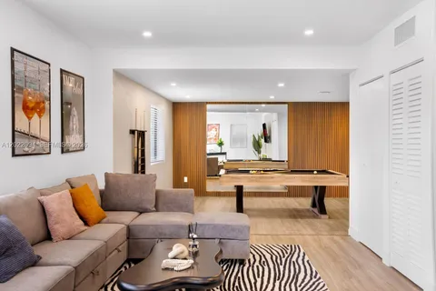 a living room with furniture pool table wooden floor and a rug