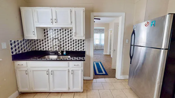 a kitchen with white cabinets and refrigerator