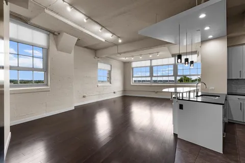 a view of a kitchen with stainless steel appliances granite countertop a stove and a wooden floors