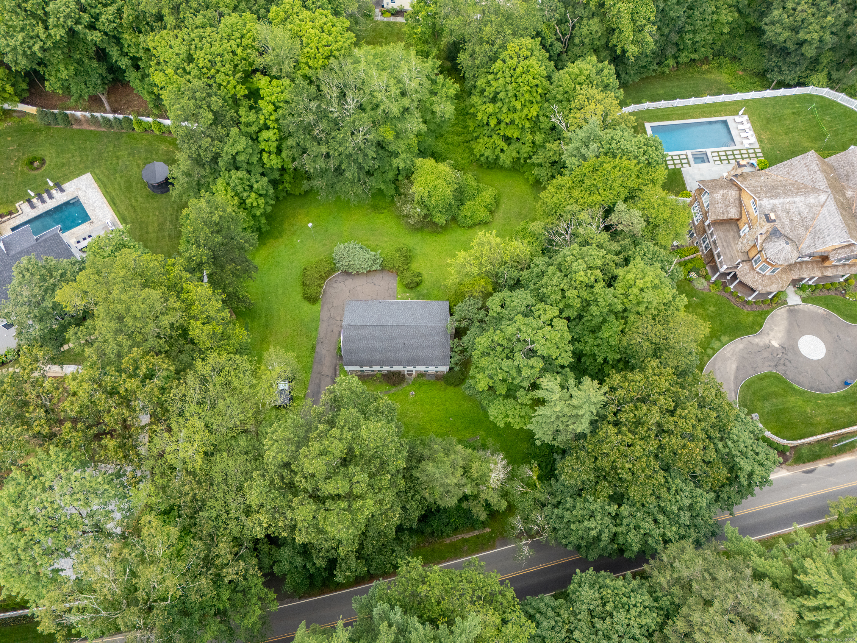 an aerial view of a house with a yard lake and trees in the back