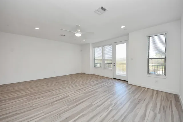 an empty room with wooden floor and windows