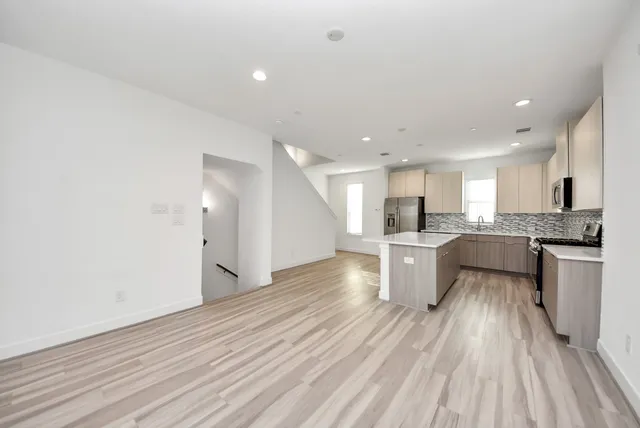 a large kitchen with a center island wooden floor stainless steel appliances and cabinets