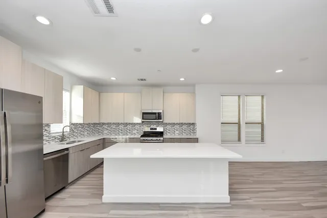 a kitchen with stainless steel appliances kitchen island granite countertop a stove a sink and a refrigerator