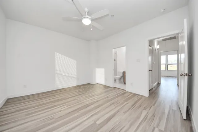 an empty room with wooden floor fan and windows