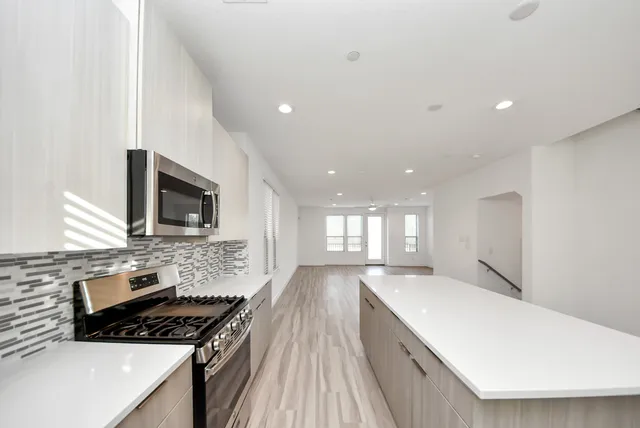 a large kitchen with stainless steel appliances kitchen island granite countertop a stove a sink dishwasher and a microwave with wooden floor