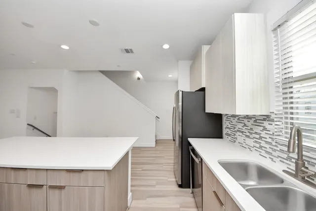 a kitchen with stainless steel appliances kitchen island granite countertop a sink and a refrigerator
