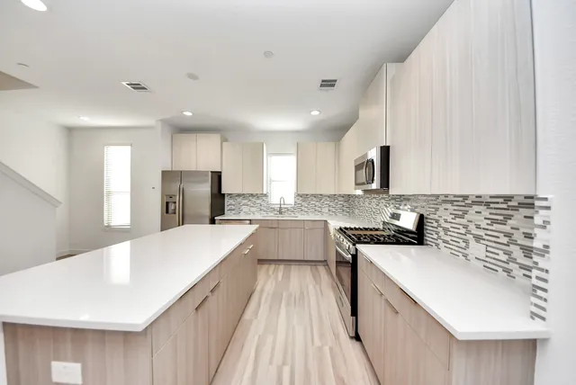 a large kitchen with a sink a counter top space stainless steel appliances and cabinets