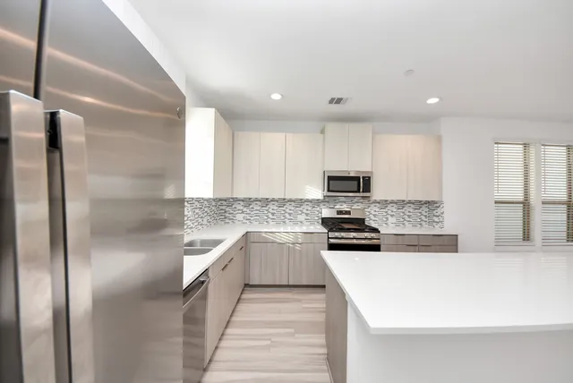 a modern kitchen with stainless steel appliances granite countertop a refrigerator and a sink