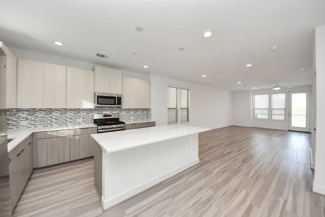 a kitchen with stainless steel appliances granite countertop a stove top oven a sink dishwasher and a refrigerator with wooden floors