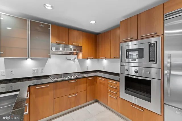 a kitchen with stainless steel appliances granite countertop a refrigerator a sink and a stove
