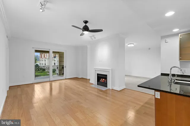 a view of a livingroom with a fireplace a ceiling fan and wooden floor