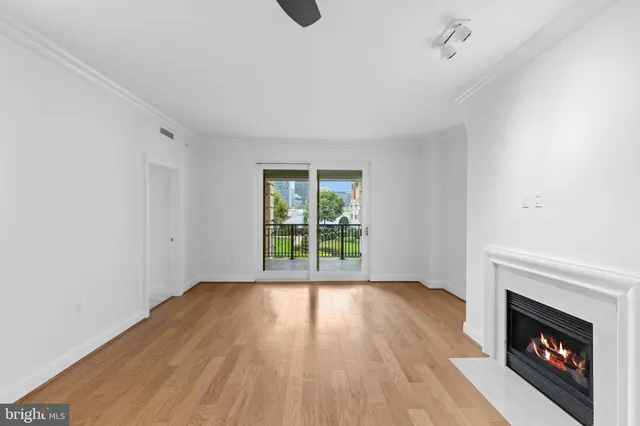 a view of an empty room with wooden floor fireplace and a window