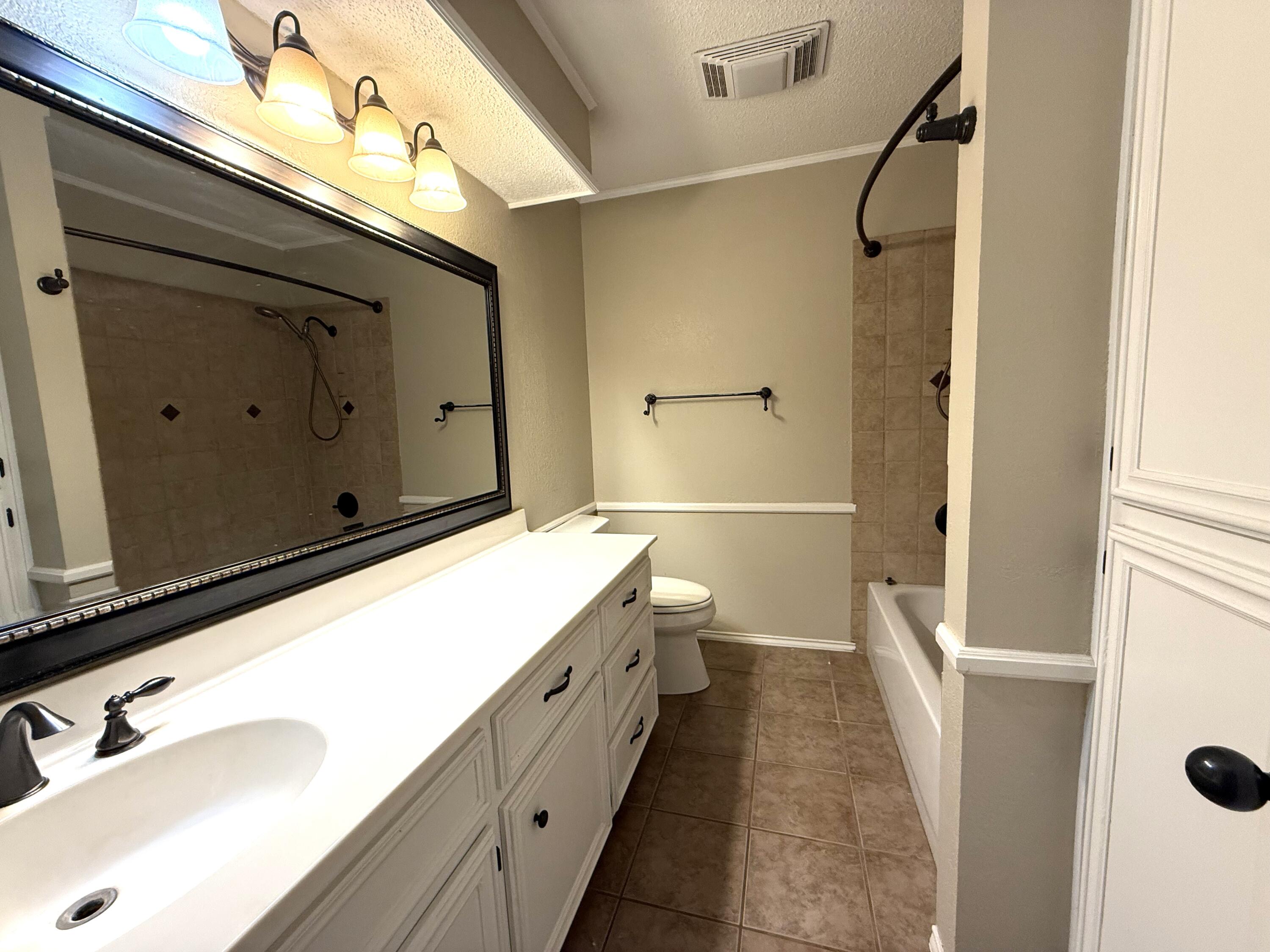 5705 87th Street Lubbock, TX 79424 - Photo 11 of 16 a bathroom with a sink a toilet and shower