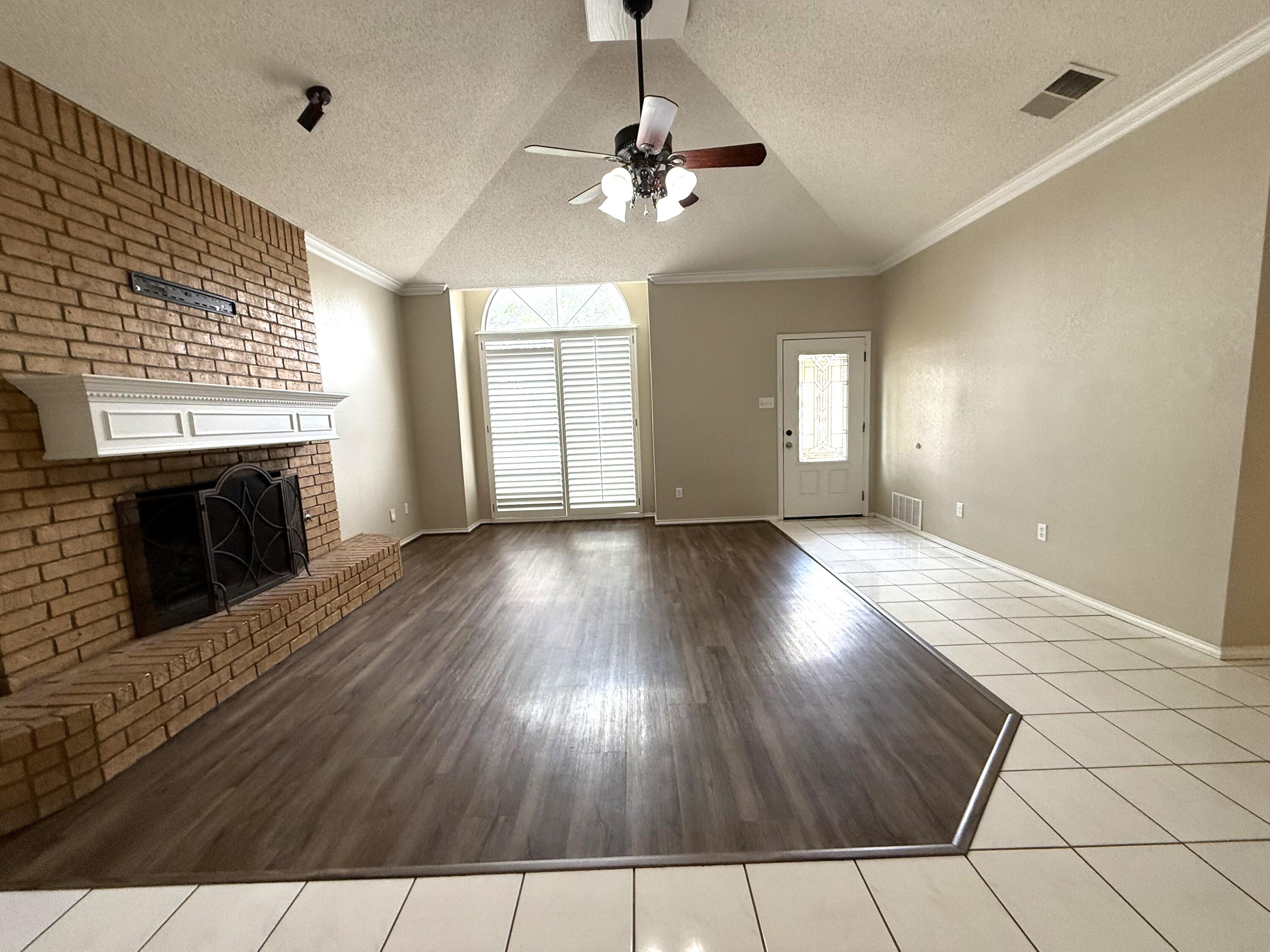 5705 87th Street Lubbock, TX 79424 - Photo 3 of 16 a view of an empty room with wooden floor fireplace and a window