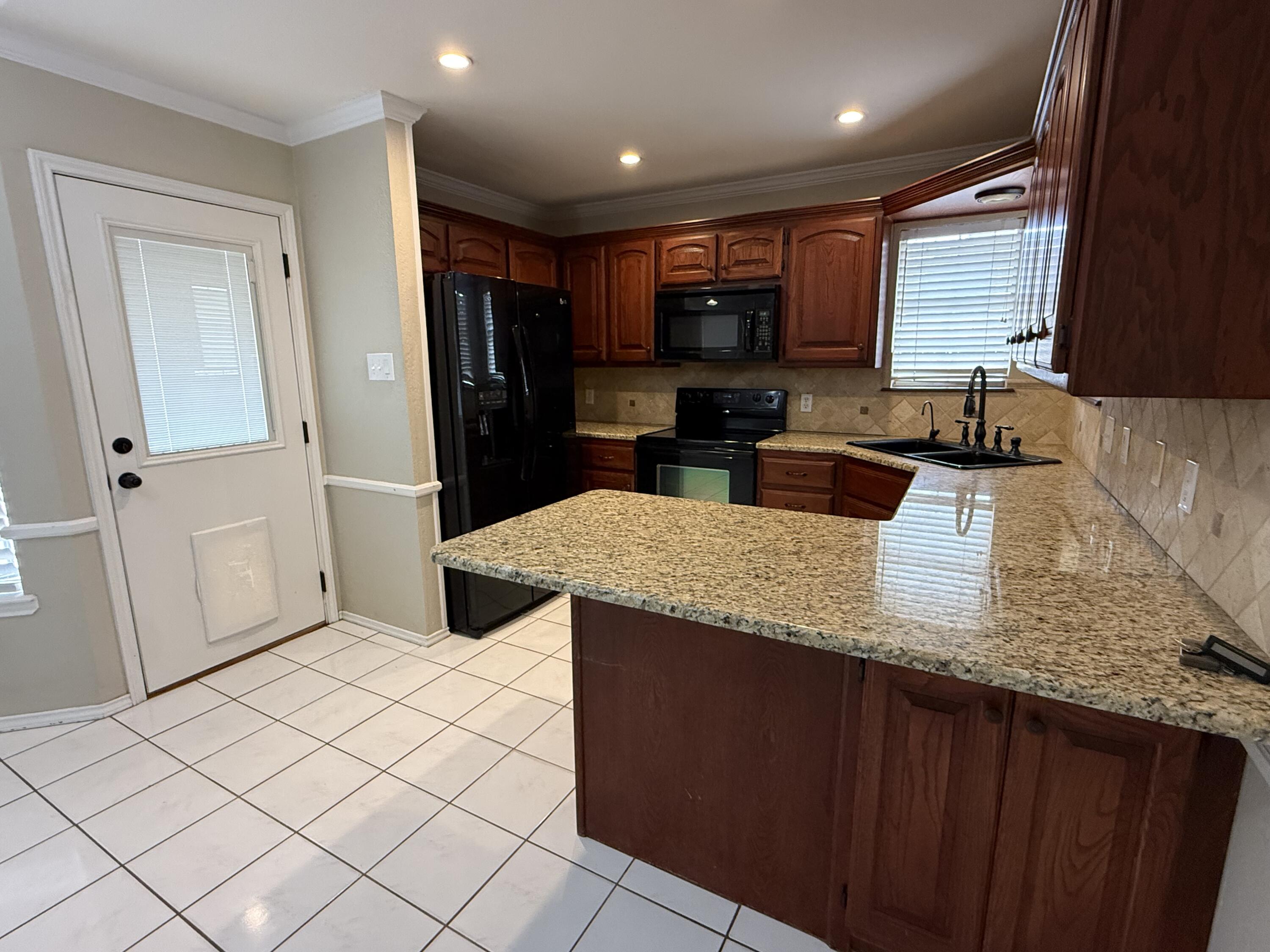 5705 87th Street Lubbock, TX 79424 - Photo 6 of 16 a kitchen with stainless steel appliances granite countertop a sink a stove and a refrigerator