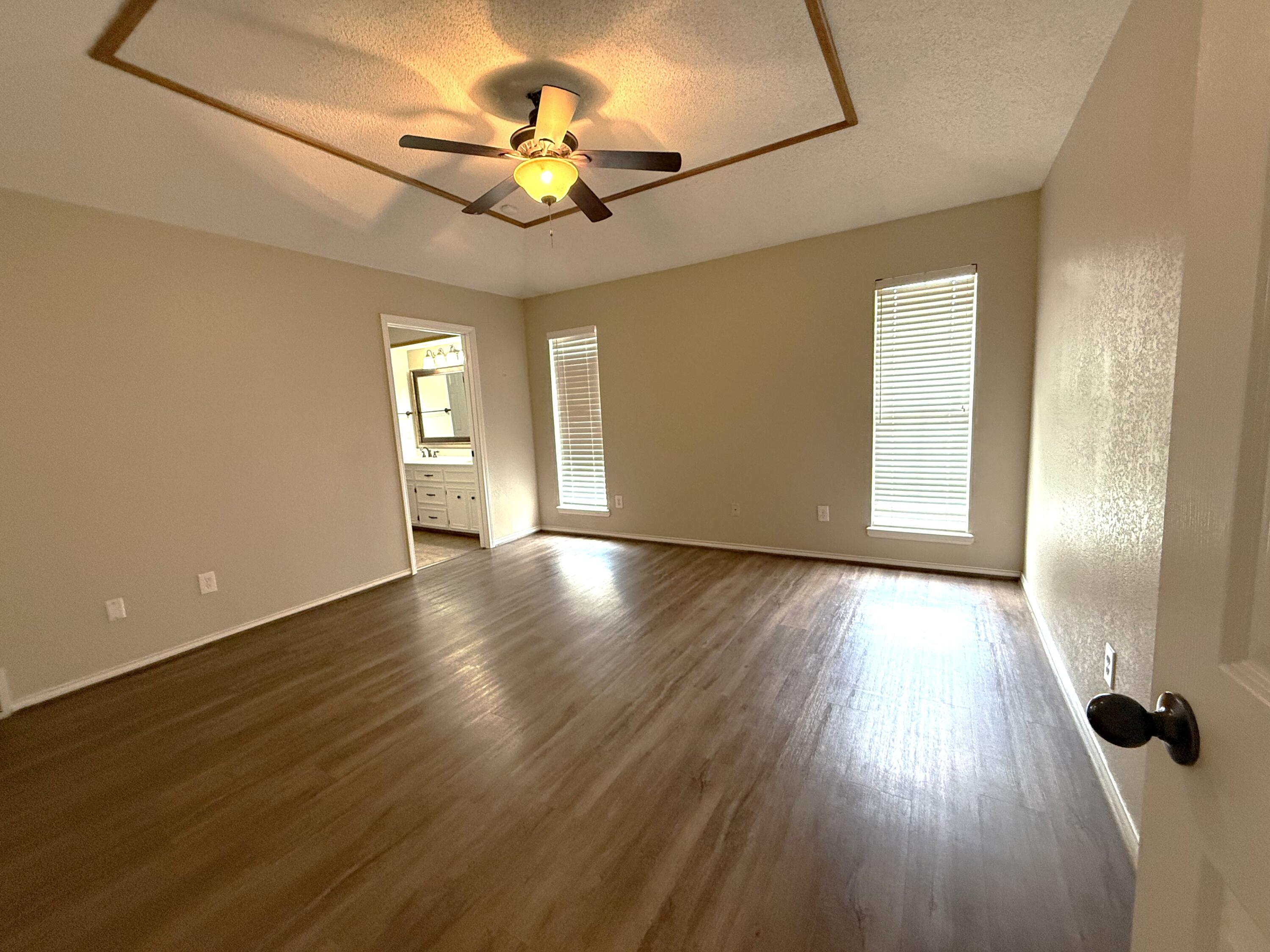 5705 87th Street Lubbock, TX 79424 - Photo 8 of 16 a view of an empty room with a window and wooden floor