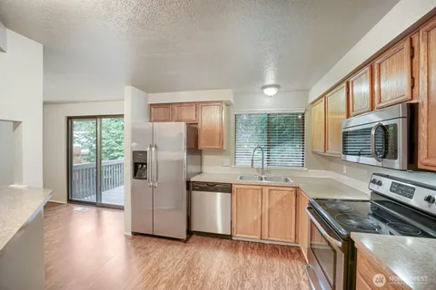 a kitchen with stainless steel appliances granite countertop a refrigerator a stove top oven and sink with wooden floor