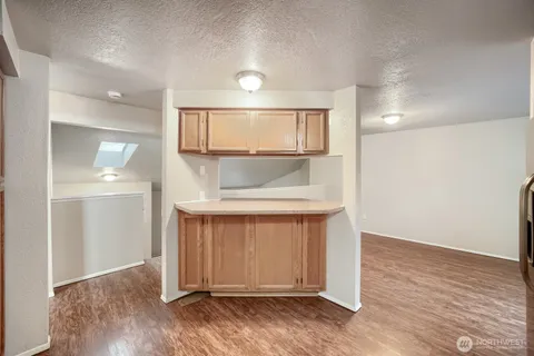 an empty room with wooden floor cabinet and windows