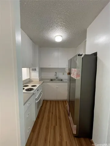 a kitchen with stainless steel appliances a refrigerator a sink a stove and white cabinets