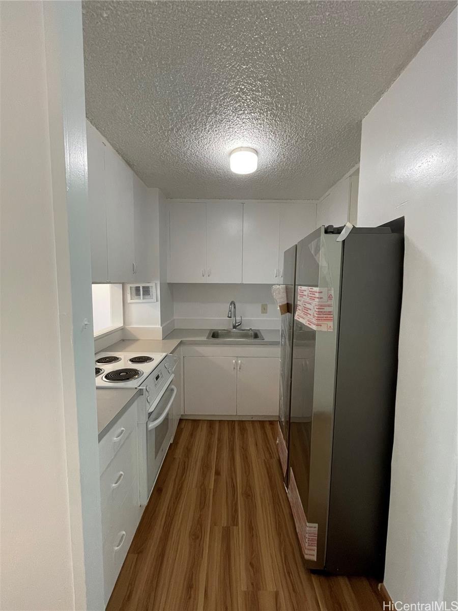 1619 Kamamalu Avenue, Unit 102 Honolulu, HI 96813 - Photo 6 of 18 a kitchen with stainless steel appliances a refrigerator a sink a stove and white cabinets