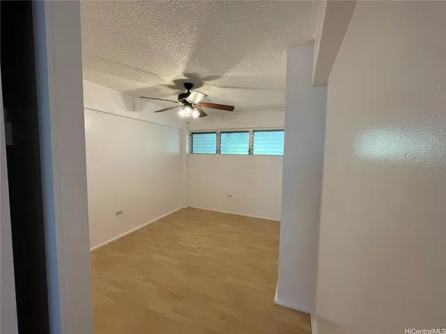 an empty room with a chandelier fan and windows