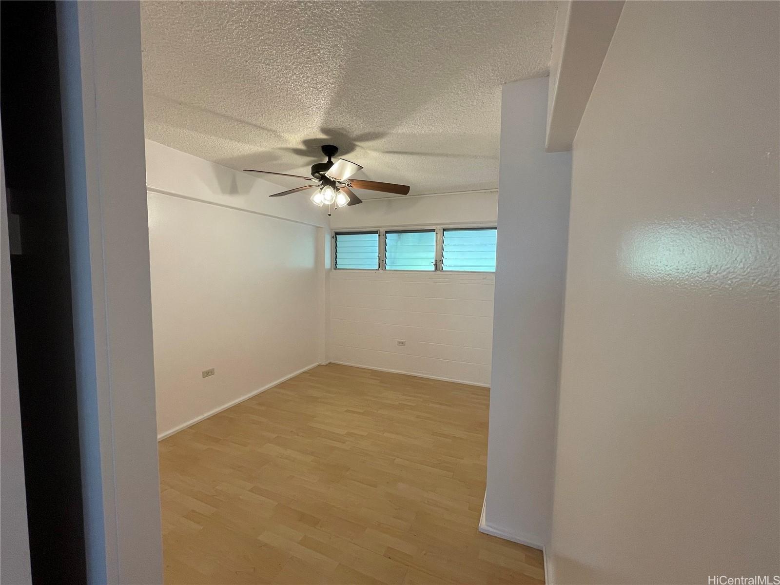 1619 Kamamalu Avenue, Unit 102 Honolulu, HI 96813 - Photo 10 of 18 an empty room with a chandelier fan and windows