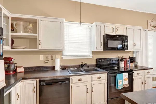 a kitchen with granite countertop a sink a stove and cabinets