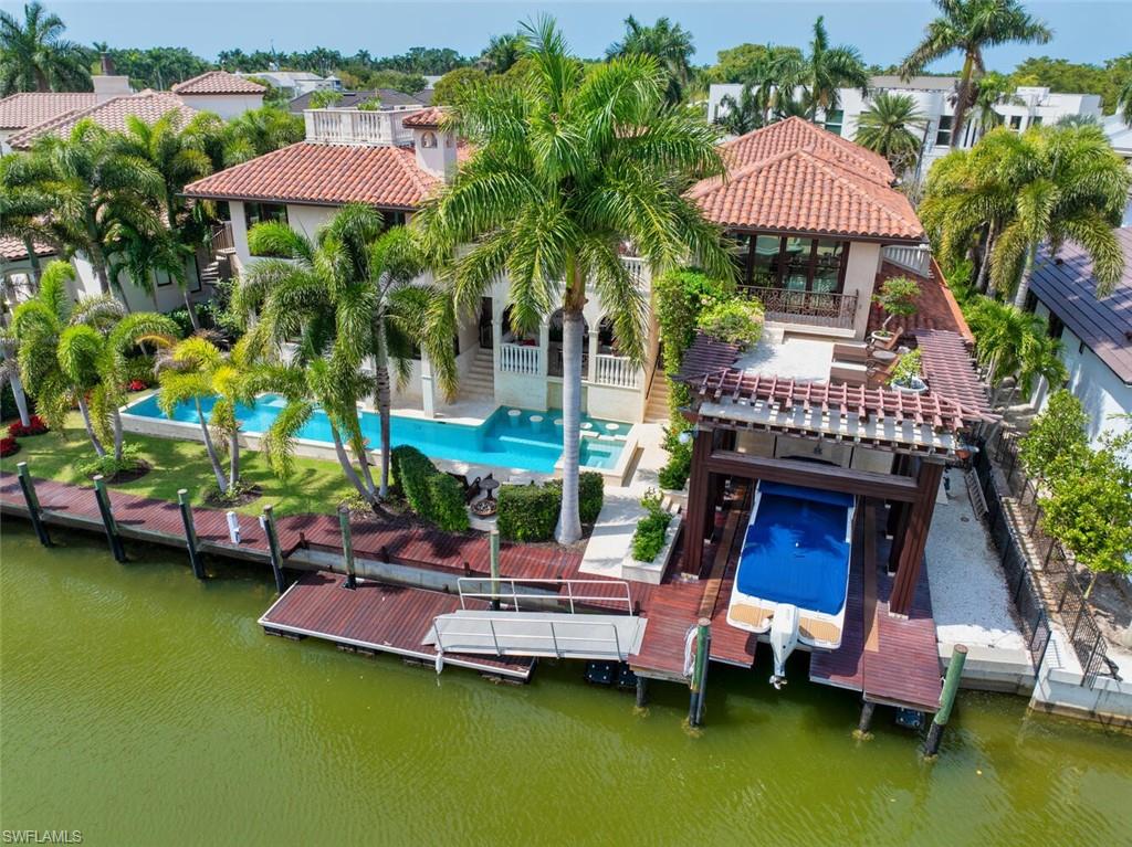 2233 Forrest Lane Naples, FL 34102 - Photo 12 of 48 a view of a swimming pool with a table and chairs under an umbrella