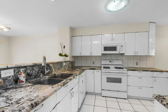 a kitchen with granite countertop white cabinets white stainless steel appliances with a sink and dishwasher