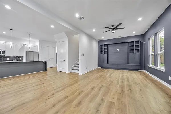 a view of an empty room with kitchen and window