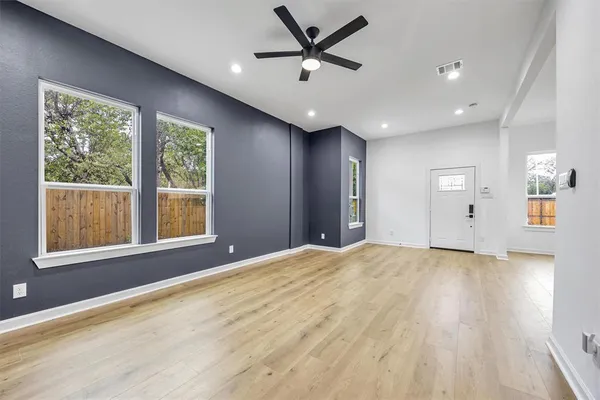 a view of an empty room with a window and wooden floor