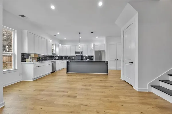 a view of kitchen with kitchen island sink refrigerator and white cabinets