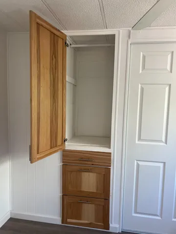 an empty room with wooden floor closet and windows
