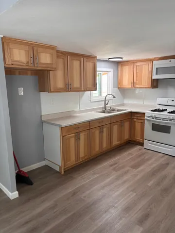 a kitchen with stainless steel appliances granite countertop a sink and cabinets with wooden floor