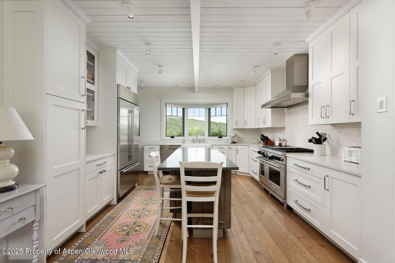 1814 Woody Creek Road Aspen, CO 81612 - Photo 14 of 52 a kitchen with stainless steel appliances granite countertop a stove a sink dishwasher and white cabinets with wooden floor