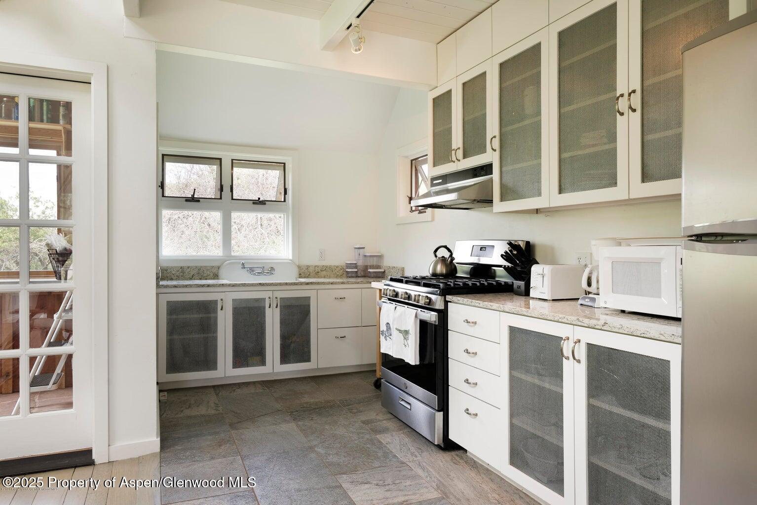 1814 Woody Creek Road Aspen, CO 81612 - Photo 50 of 52 a kitchen with stainless steel appliances granite countertop a stove and cabinets