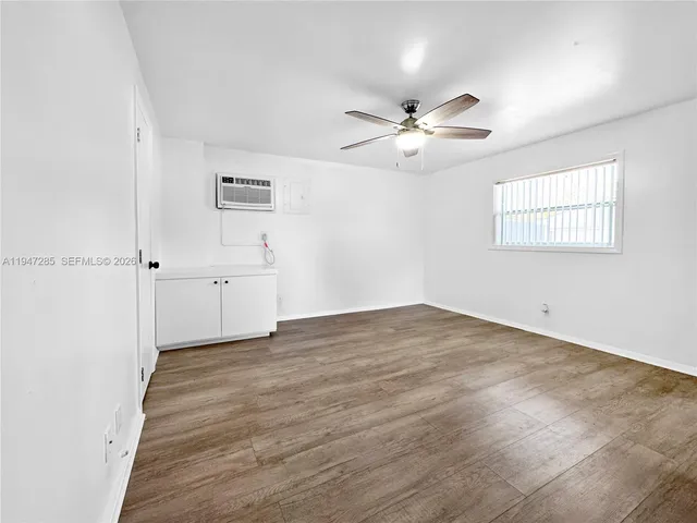 an empty room with wooden floor ceiling fan and windows