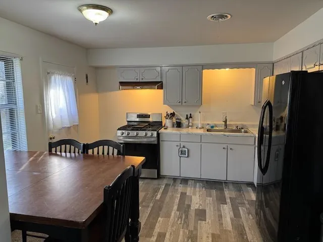 a kitchen with a refrigerator a stove a sink dishwasher with a dining table and chair