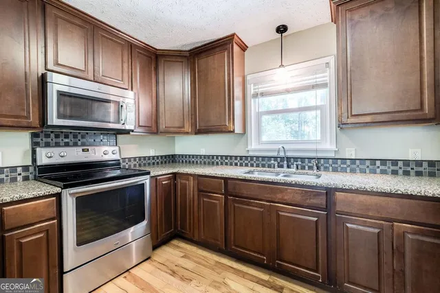 a kitchen with granite countertop cabinets stainless steel appliances and a window