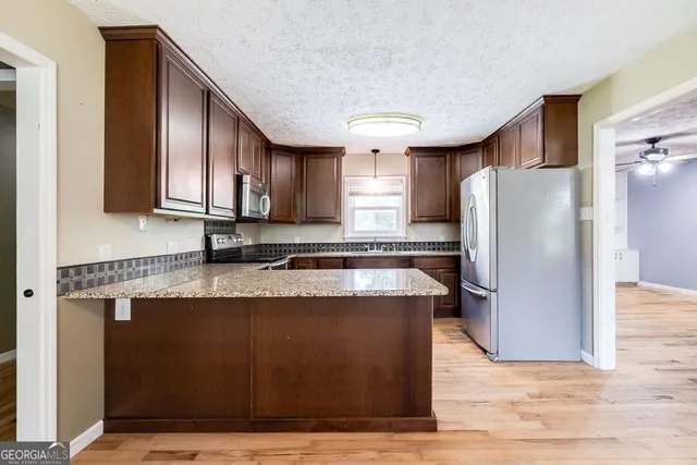 a kitchen with stainless steel appliances granite countertop a refrigerator a sink a stove a microwave and island