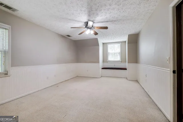 an empty room with windows and ceiling fan