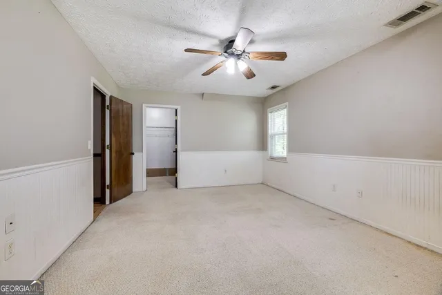 an empty room with chandelier fan and windows