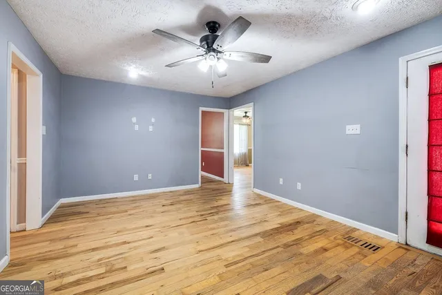 an empty room with chandelier fan and windows
