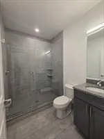 a bathroom with a granite countertop sink a toilet and shower