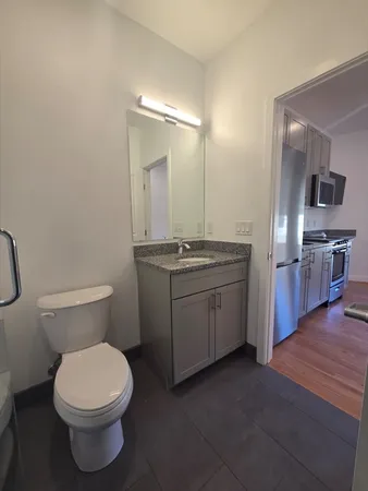a bathroom with a granite countertop toilet sink and mirror