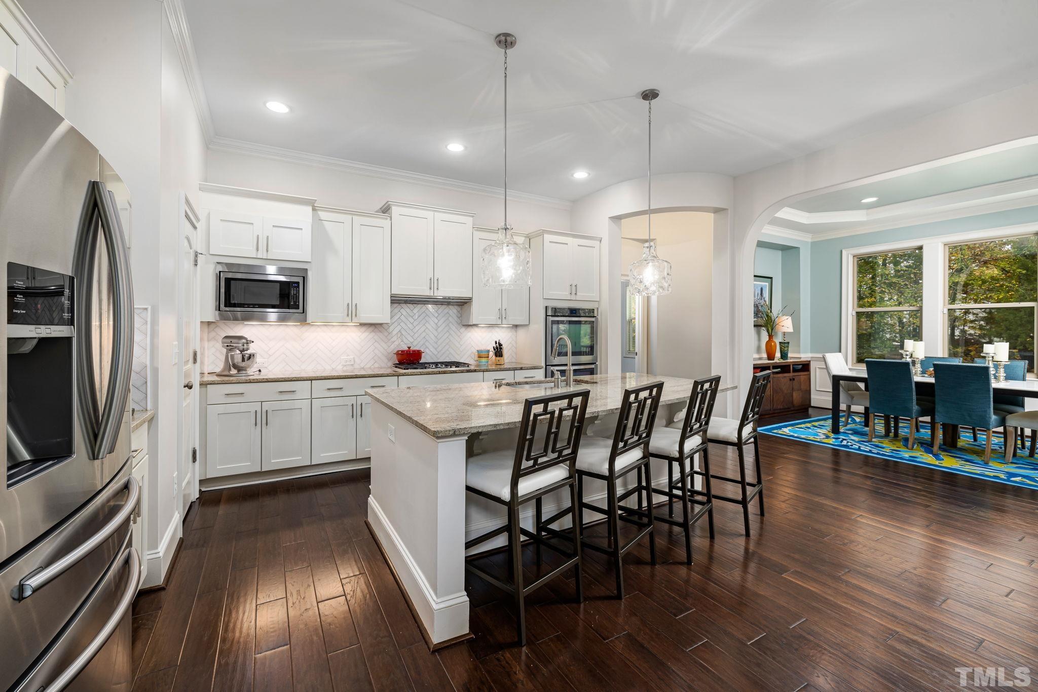 4526 Farrington Road Durham, NC 27707 - Photo 9 of 42 a kitchen with stainless steel appliances granite countertop a refrigerator a stove top oven a sink dishwasher and white cabinets with wooden floor