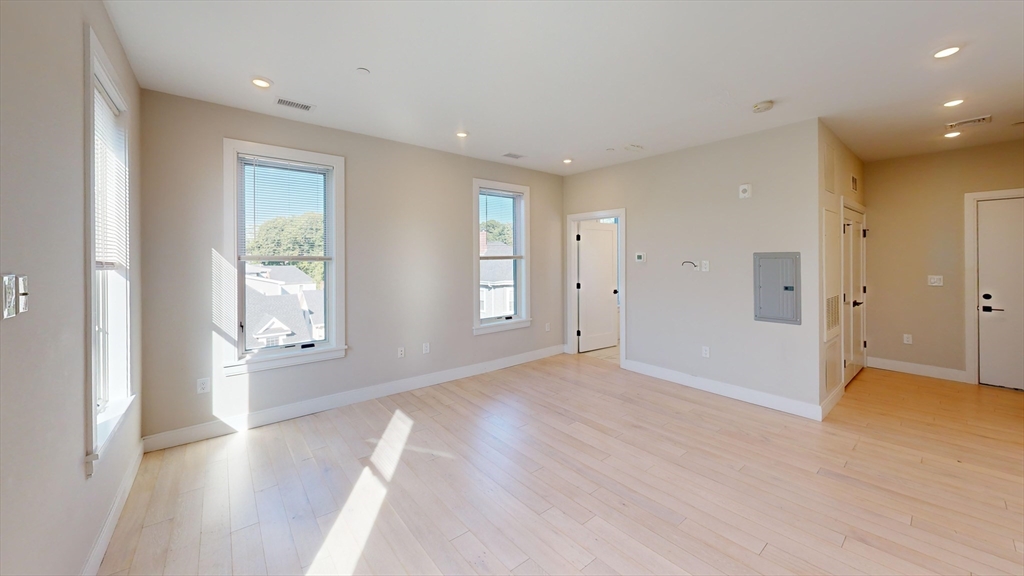 197 Green Street, Unit 401 Boston, MA 02130 - Photo 3 of 5 a view of an empty room with wooden floor and a window