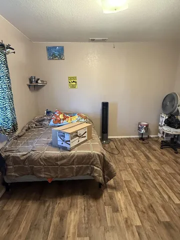 a view of a hallway with wooden floor and a cabinet